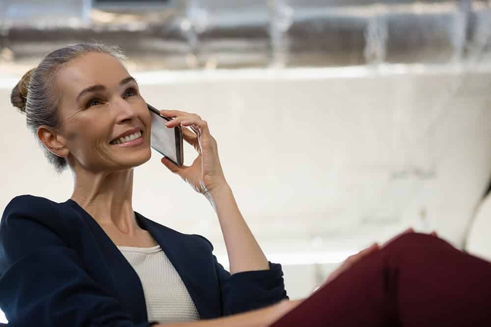 Smiling businesswoman communicating on smart phone at office