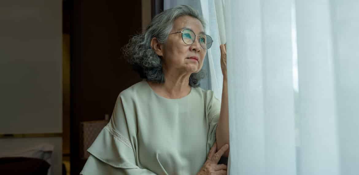 Elderly woman looked outside appears thoughtful in a quiet moment of contemplation