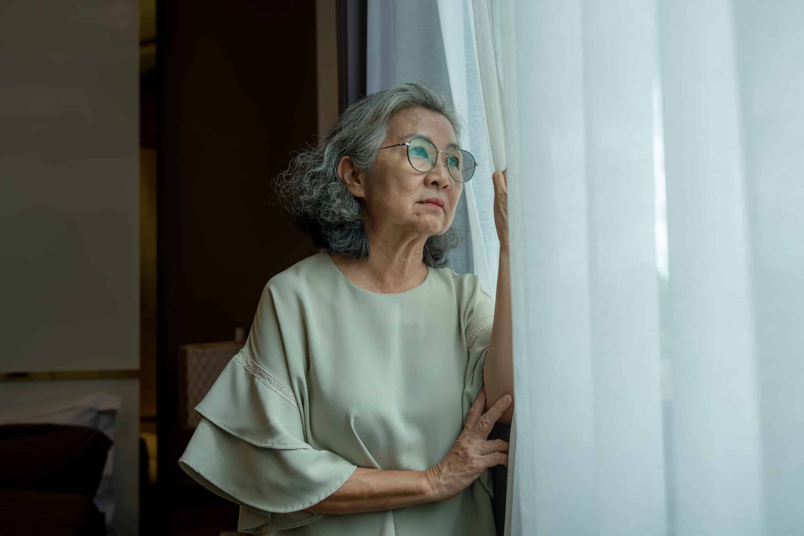 Elderly woman looked outside appears thoughtful in a quiet moment of contemplation